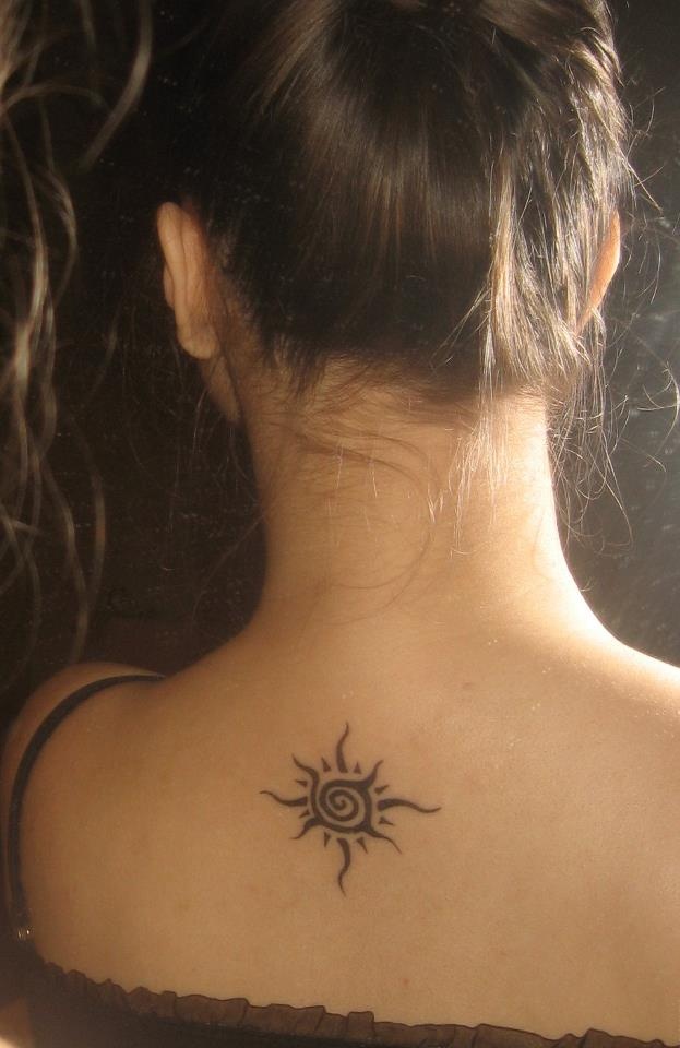 Small black spiral sun tattoo on upper back