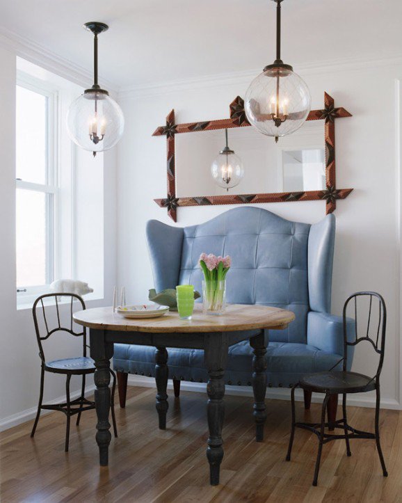 Blue tufted wingback banquette with rustic table and globe pendants