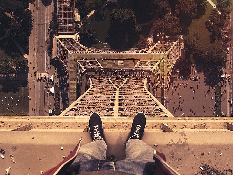 First-person view of sneakers on an Eiffel Tower ledge looking straight down