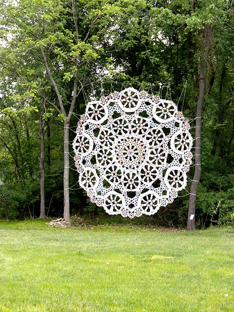 Large white lace installation hung between trees