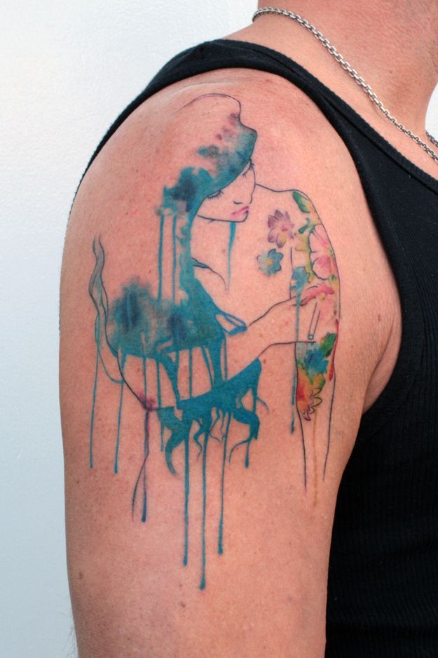Watercolour portrait tattoo with teal drip effects on the shoulder