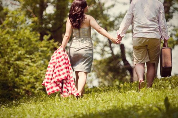 Couple walking through tall grass after picnic