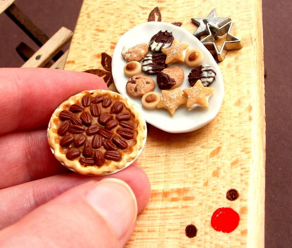 delicious-mini-foods01 Miniature pecan pie held in fingers beside a plate of tiny cookies