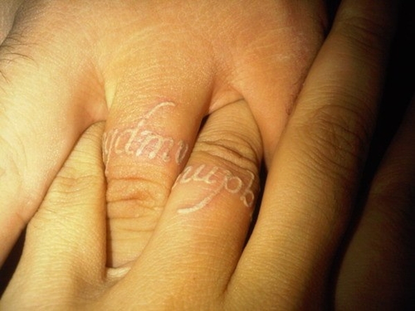 Matching white ink ring finger tattoos