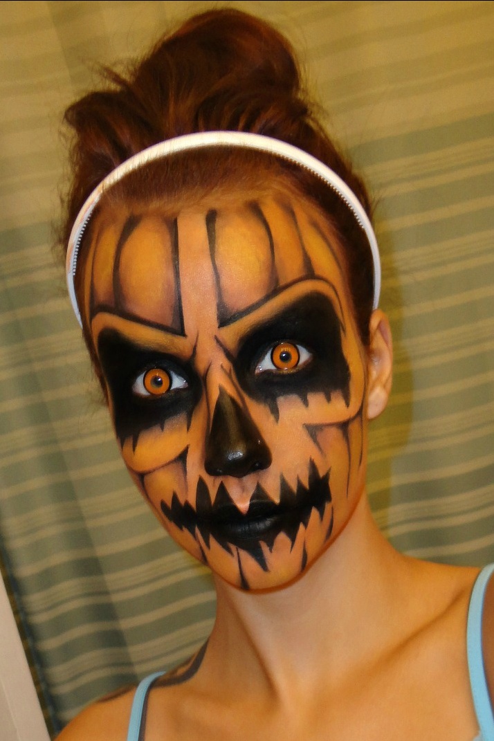 Orange jack-o-lantern face paint with glowing contacts