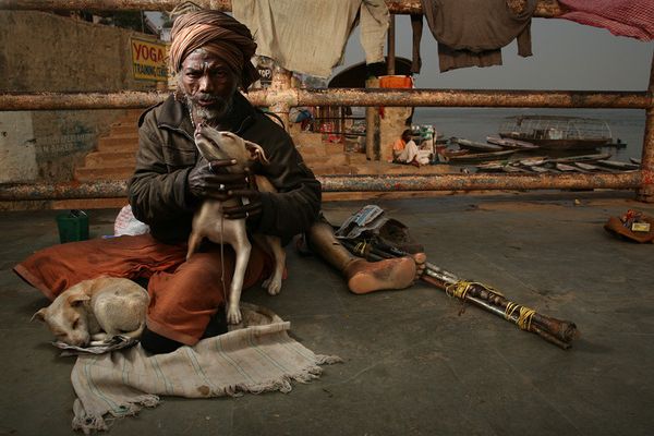 awesome-india-photos14 Man with turban holding a dog near crutches and a prosthetic leg
