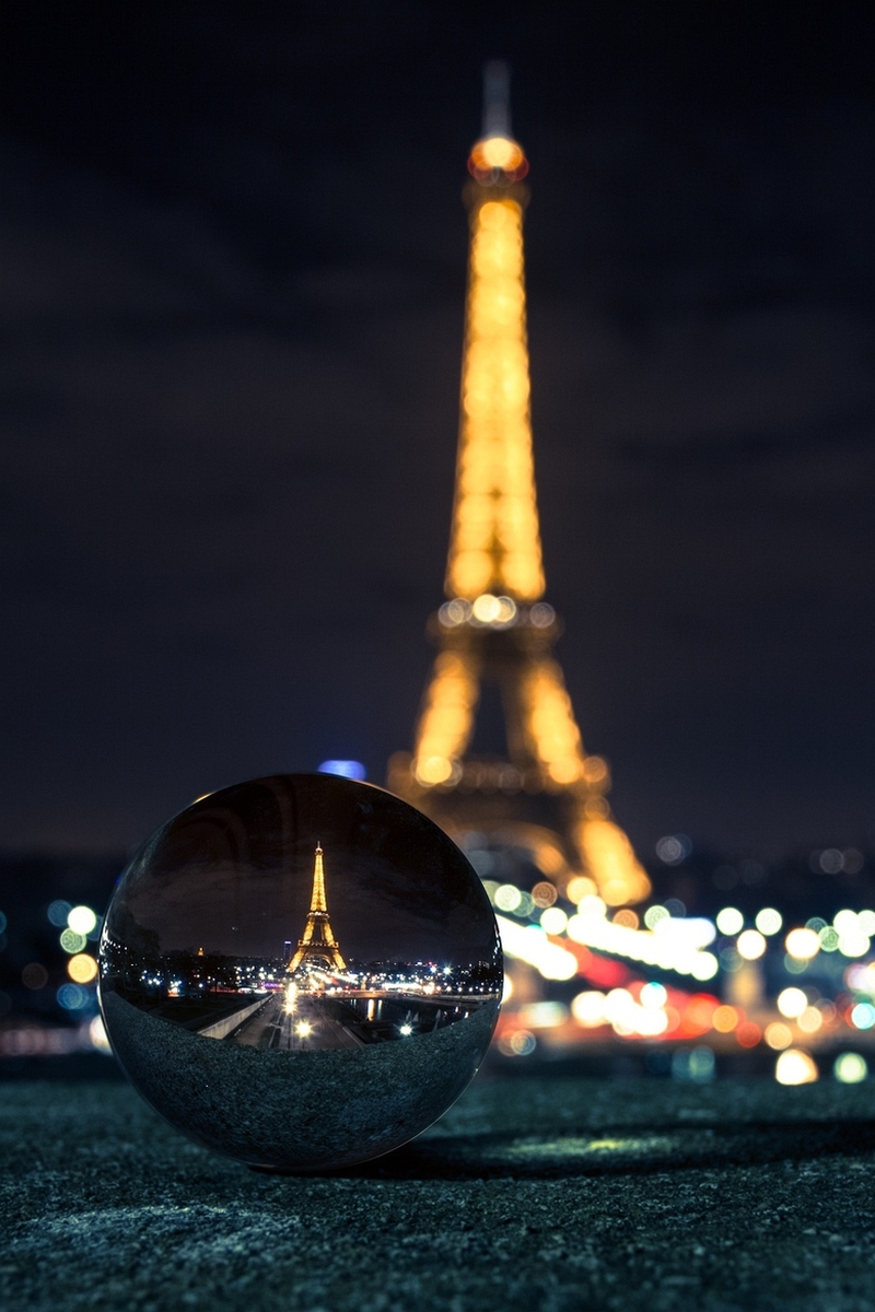 Crystal ball on a ledge reflecting a sharp night view of the Eiffel Tower