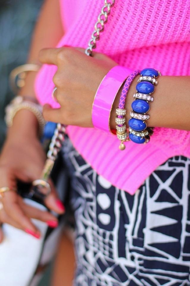Neon pink knit with cobalt cabochon bracelets over black-and-white geometric print