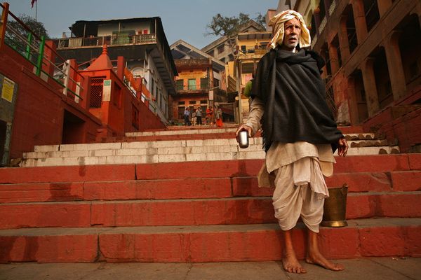 awesome-india-photos13 Elderly man with metal cup on red-painted ghat steps