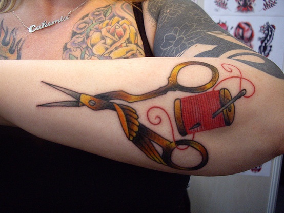 Neo-traditional forearm tattoo of vintage shears and a red spool of thread
