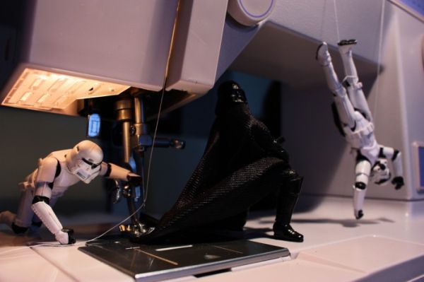 Darth Vader and stormtroopers at a sewing machine repairing a cape