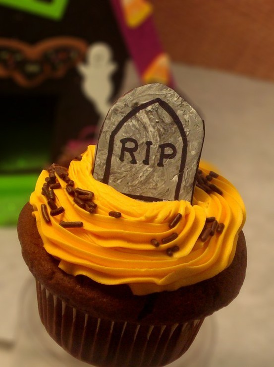 Orange frosted cupcake with RIP tombstone topper