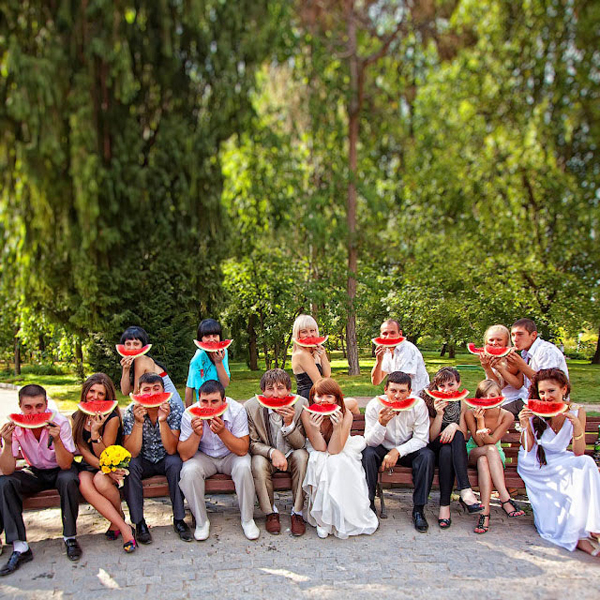 Wedding group holding watermelon slices as matching smiles