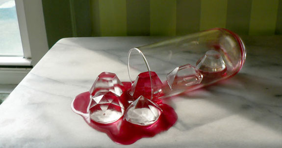 Faceted gemstone diamond ice cubes spilled with red drink