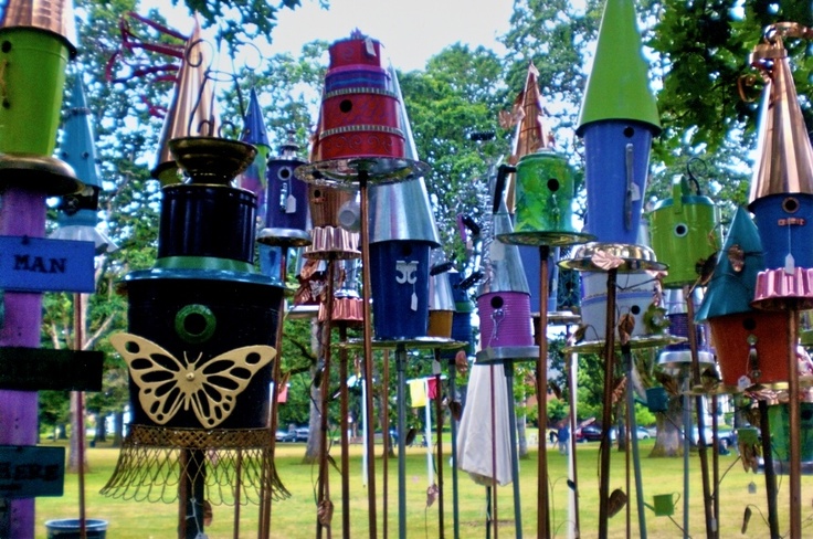Colorful birdhouses on tall poles in a lawn
