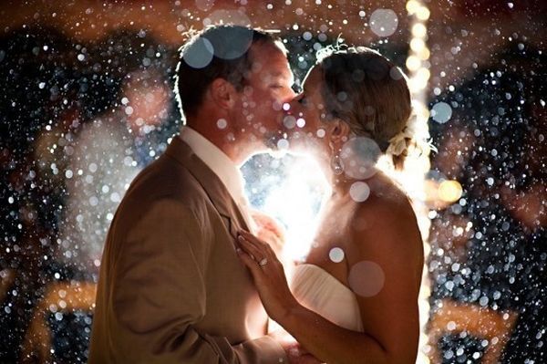 Backlit couple kissing in rain or snow with bokeh lights