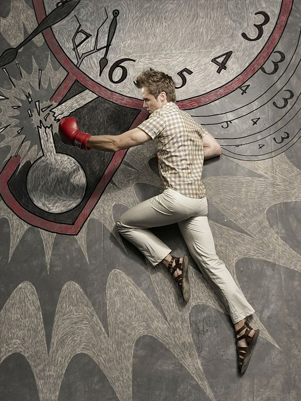 Man with red boxing glove punching a chalk lightbulb amid clock motifs