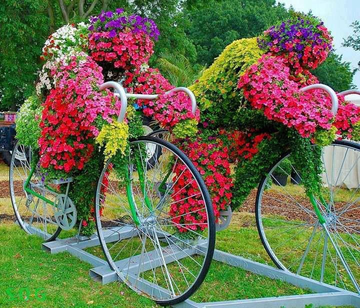 Flower-covered cyclist sculptures with real bike parts